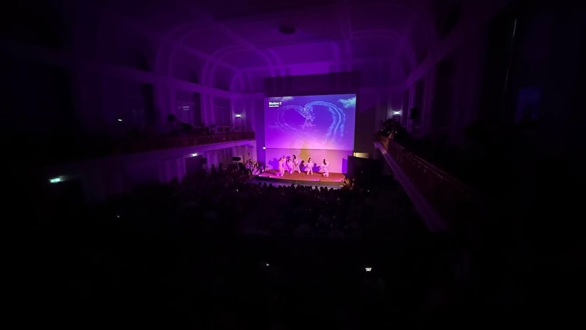 Blick von der Empore in den dunklen, violett beleuchteten Saal
