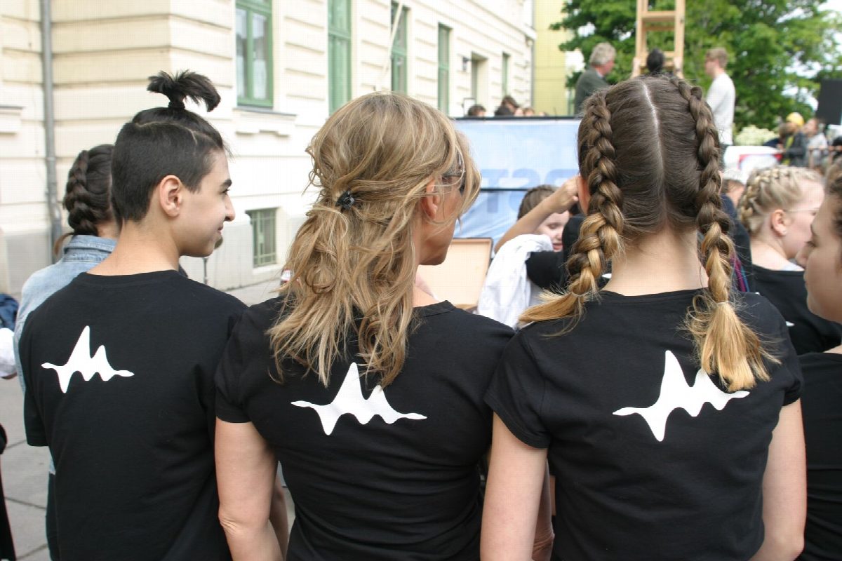 Drei Rücken mit dem Studio-Logo auf schwarzen Shirts