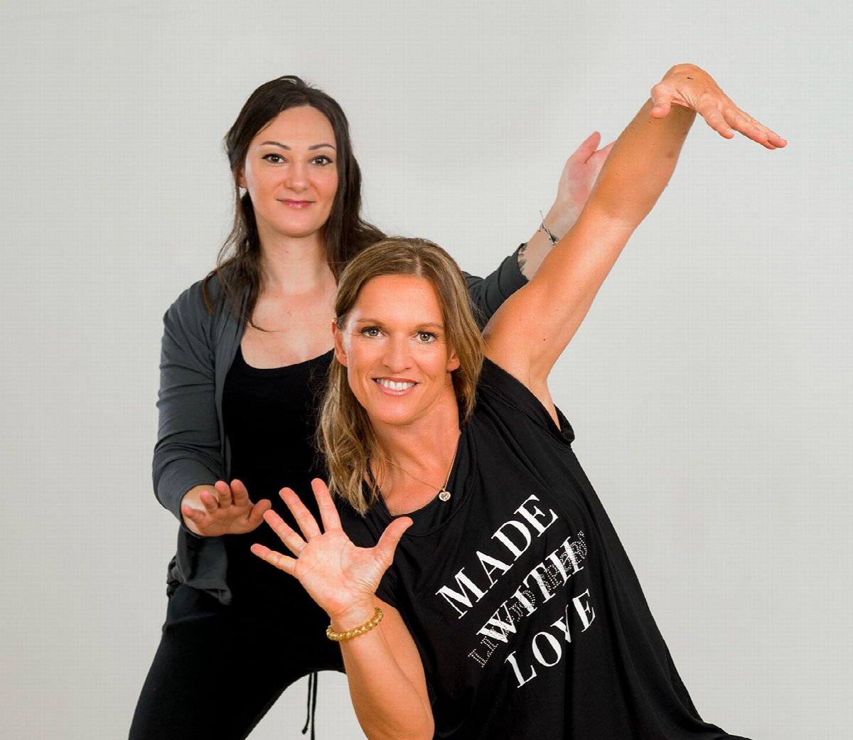 Zwei Frauen in einer gemeinsamen Tanzpose vor heller Wand