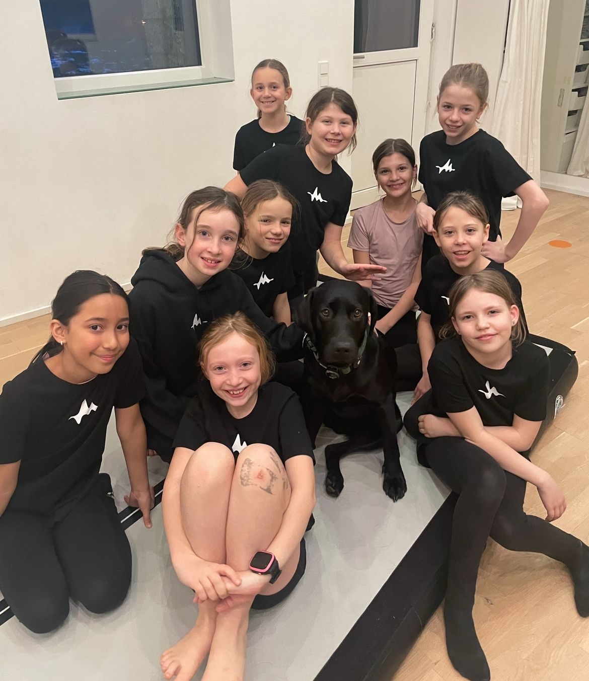Kindergruppe im Studio mit einem schwarzen Labrador