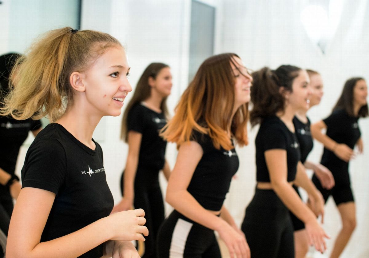 Jugendliche in Studio-Shirts stehen lachend in einer Reihe