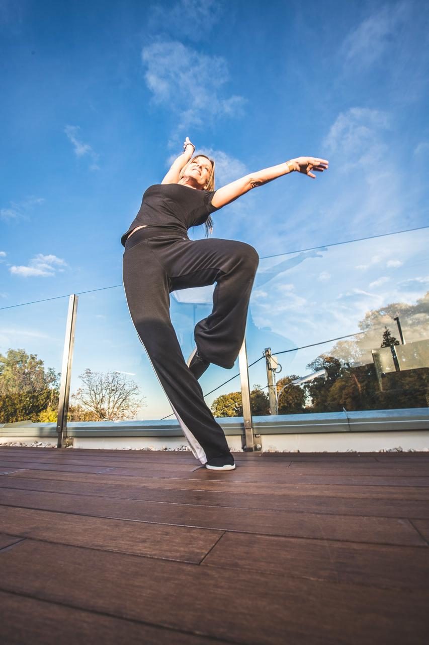 Monica Czech in einem Sprung auf der Dachterrasse, blauer Himmel